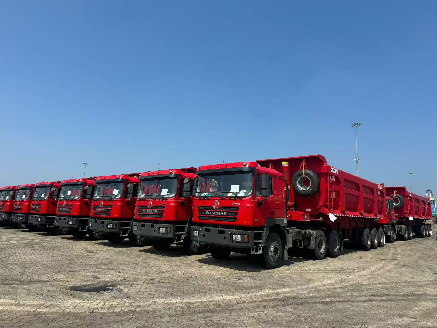 Heavy duty truck production line in China, featuring Sinotruk or Shaanxi heavy trucks, modern industrial facility with blue sky background
